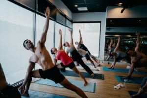 Class of men and women practicing Bikram Yoga in triangle pose