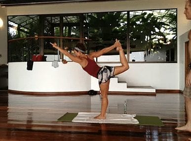 Lady demonstrating standing bow pose at Pura Vida Spa in the Hot Yoga Studio at the yoga retreat in costa rica