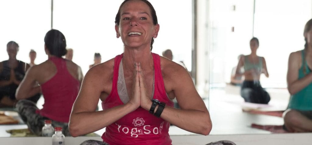 Teacher in YogaSol Tank in prayer position smiling and saying namaste after hot hiit class